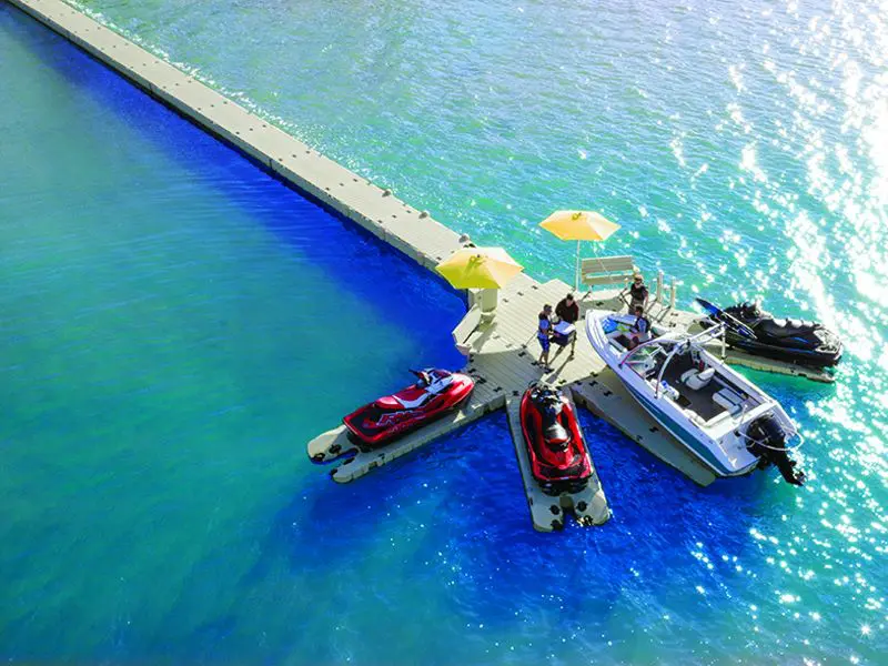A boat dock with people on it and boats in the water.