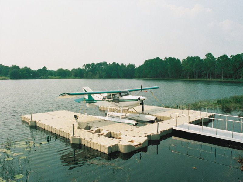 A plane is sitting on the water near some docks.
