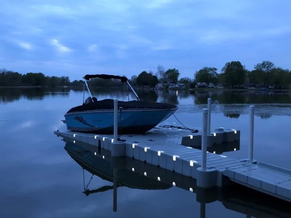 A boat parked at the dock in front of a lake in the evening